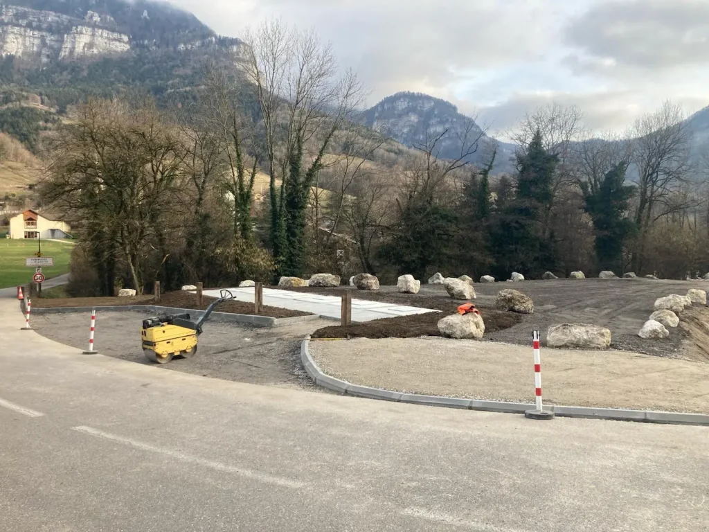 Travaux de terrassement et aménagement d'un espace de stationnement avec pose de bordures, compactage et enrochement paysager par l'entreprise Arnaud Genève à La Sure en Chartreuse